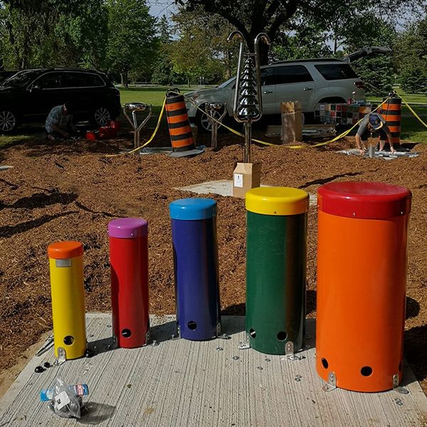 set of 5 rainbow coloured outdoor playground drums in the process of being installed in the belleville rotary music garden